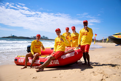 Life savers in yellow uniforms with a red rescue boat on a beach